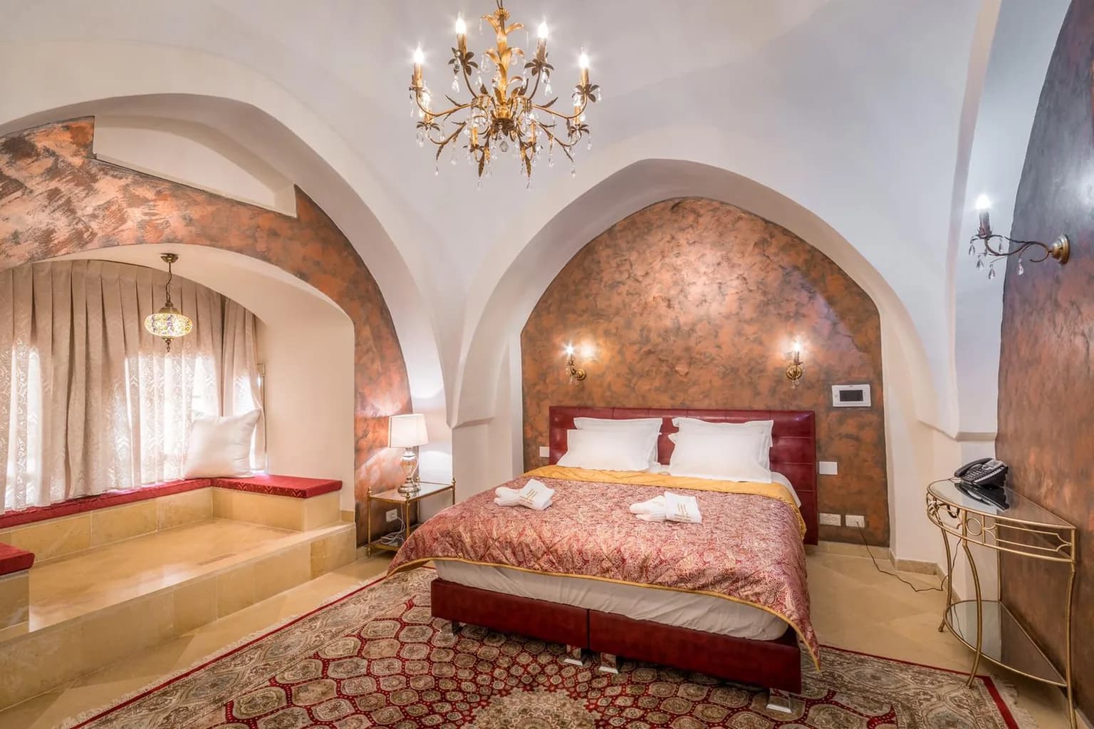 Luxurious vaulted bedroom with chandelier and alcove.